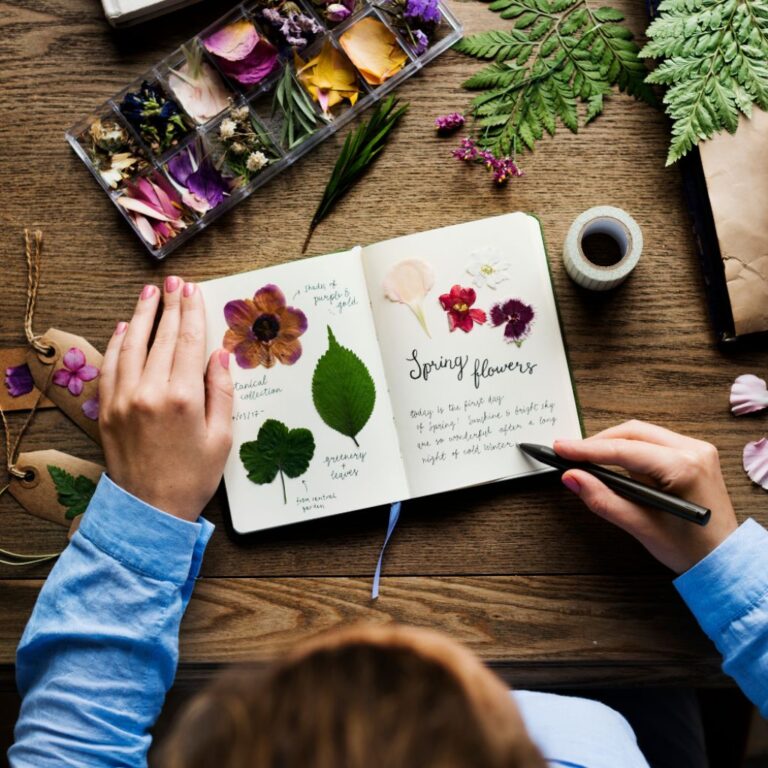 a man drawing leaves and flowers on a notebook